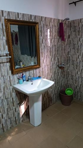 a bathroom with a white sink and a mirror at Location meublée in Lomé