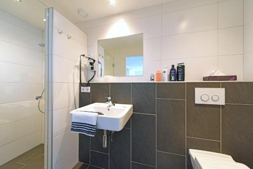 a white bathroom with a sink and a shower at Hotel Kodde in Aagtekerke