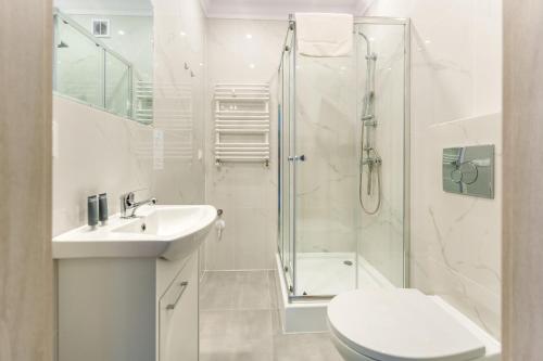 a white bathroom with a shower and a toilet and a sink at Apartament Tropikalny by Holiday&Sun in Grzybowo