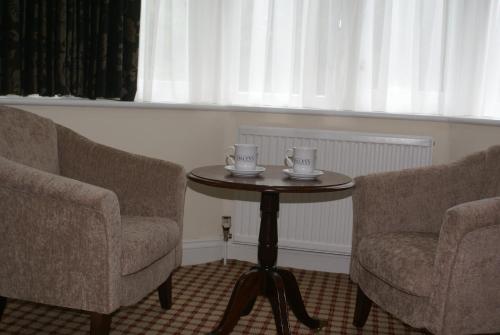 two chairs and a table with two cups on it at Haley's Hotel in Leeds