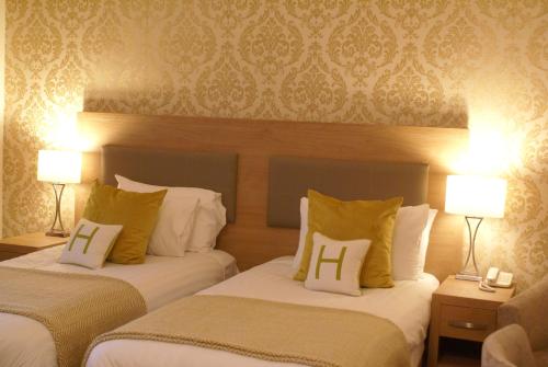 two beds in a hotel room with two lamps at Haley's Hotel in Leeds
