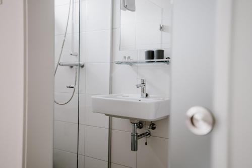 ein weißes Badezimmer mit einem Waschbecken und einem Spiegel in der Unterkunft Ons Kotje in Aagtekerke