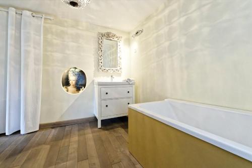 La salle de bains est pourvue d'une baignoire et d'un miroir mural. dans l'établissement Le Boudoir de Stanislas - Appt au cœur de Nancy, à Nancy