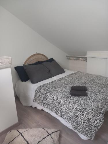 ein Schlafzimmer mit einem Bett mit einer schwarzen und weißen Decke in der Unterkunft Maison de charme L'hirondelle en Auvergne in Champs