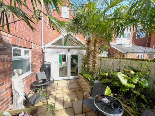 a patio with a palm tree and tables and chairs at Melbury Rooms & Studios in Exeter