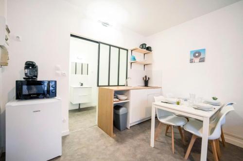 una pequeña cocina blanca con mesa, mesa pequeña y sillas en Studio - centre historique, en Agde