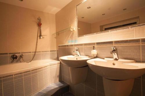 a bathroom with two sinks and a tub and a mirror at Relax Vila se zahradním wellness in Ostrava