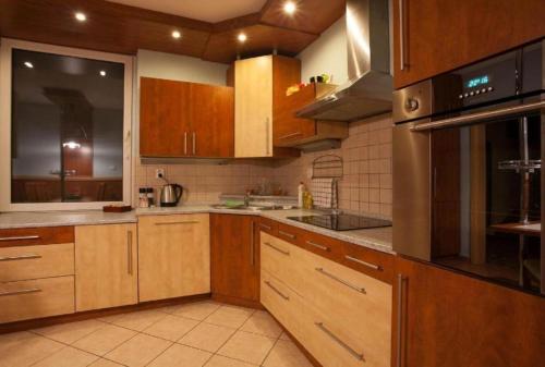 a kitchen with wooden cabinets and stainless steel appliances at Relax Vila se zahradním wellness in Ostrava