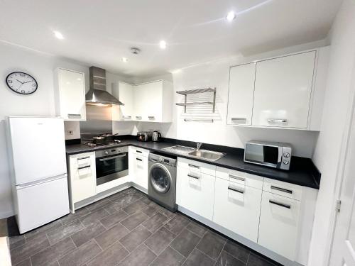 a kitchen with white cabinets and a washer and dryer at Apartment 1 - The Railway Apartment Building by Blue Skies Stays in Darlington