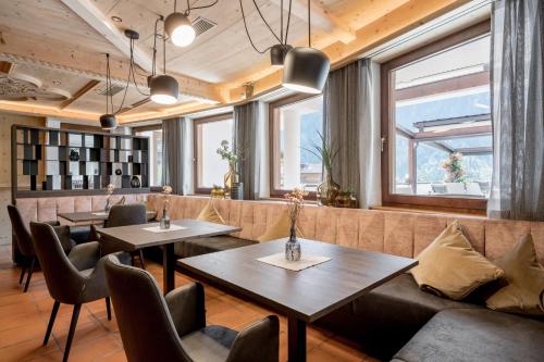a restaurant with tables and chairs and windows at Wellness & Relax Hotel Milderer Hof in Neustift im Stubaital