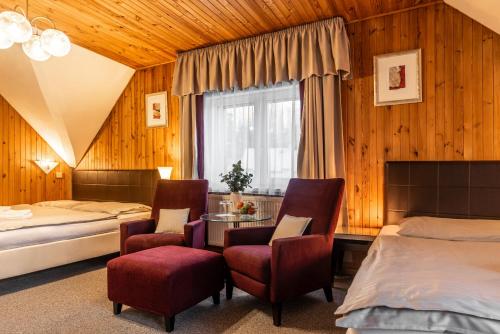 Hotel Schwarz في Nové Hamry: غرفة نوم بسريرين وطاولة وكراسي