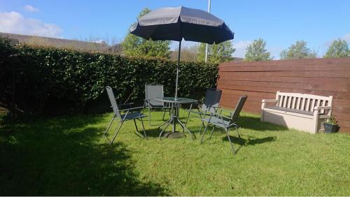 a table and chairs with an umbrella and a bench at Summer House Sleeps 6 , 2 Large Parking Spaces, walking distance to Cardiff Bay and City Centre in Cardiff