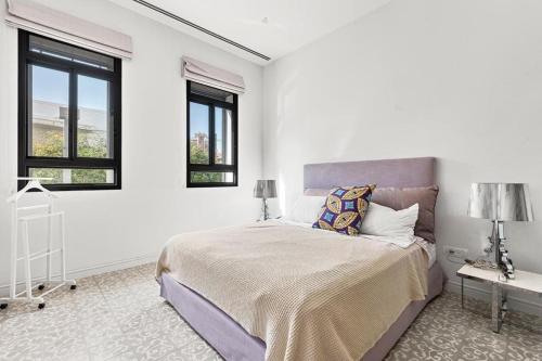 a white bedroom with a bed and two windows at Modern 2BR Private House Neve Tsedek by HolyGuest in Tel Aviv