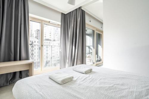 um quarto com uma cama branca com duas toalhas em VipWarsawApartments Chalcedon Mennica Residence em Varsóvia