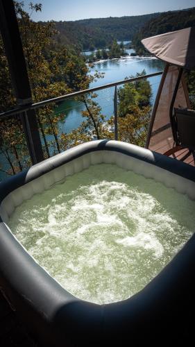 a jacuzzi tub with a view of a river at MREŽNICA - ZELENA BAJKa in Generalski Stol