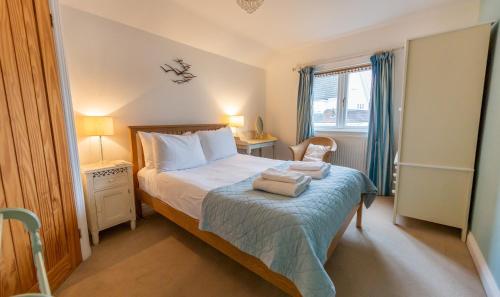 a bedroom with a bed with two towels on it at Wherry Cottage, Sleeps 8 in Southwold
