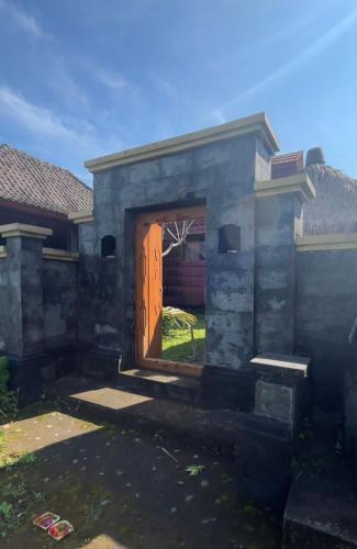 dom z drewnianymi drzwiami na dziedzińcu w obiekcie Villa & Home Stay Kubu Alit Besakih w mieście Besakih
