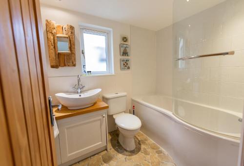 ein Badezimmer mit einem Waschbecken, einem WC und einer Badewanne in der Unterkunft Wherry Cottage, Sleeps 8 in Southwold