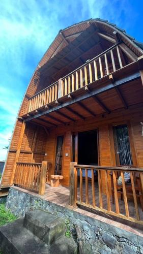 duży drewniany dom z werandą i balkonem w obiekcie Villa & Home Stay Kubu Alit Besakih w mieście Besakih