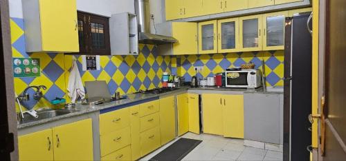 eine gelbe Küche mit gelben Schränken und einer Mikrowelle in der Unterkunft Bonjour Travellers Hostel in Hyderabad