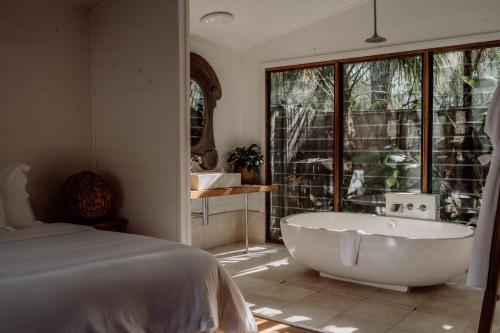 um quarto com uma banheira, uma cama e uma janela em The Boathouses at Leaves & Fishes em Lovedale