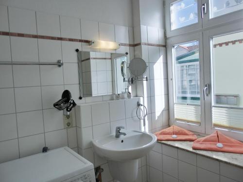 uma casa de banho branca com um lavatório e um espelho em Ferienwohnung LVC11 em Graal-Müritz