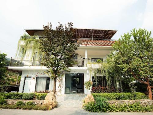 a large white house with a tree in front of it at Vian Rock Hill Homestay in Hanoi