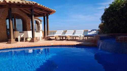 einen Pool mit Stühlen und einem Pavillon in der Unterkunft Villa Puerto Blanco in Calpe