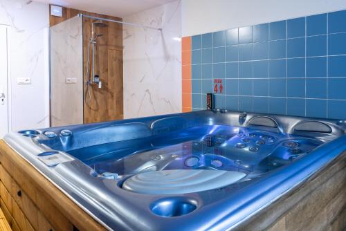 uma banheira azul numa casa de banho com azulejos azuis em Hotel Schwarz em Nové Hamry