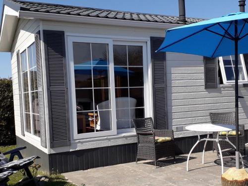 a patio with a table and chairs and an umbrella at Chalet with garden near Wadden Sea in Tzummarum