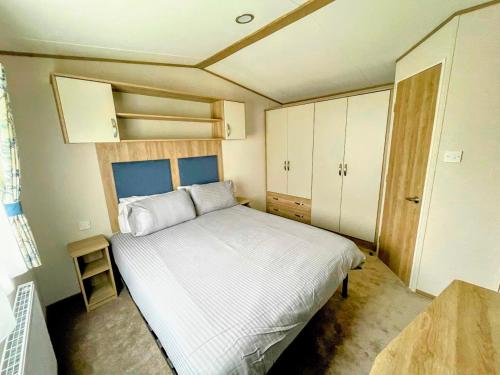 um pequeno quarto com uma cama branca e armários em Dog and Duck Leisure Park em Kent