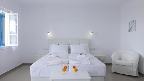 a white bedroom with a white bed and a chair at Limnionas Bay Village Hotel in Marathokampos