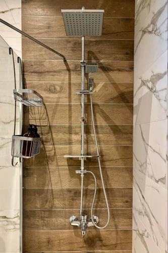 a shower in a bathroom with a wooden wall at Maya Suites N.Moudania in Nea Moudania