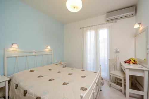 a white bedroom with a bed and a window at Irini Studios in Agia Anna Naxos