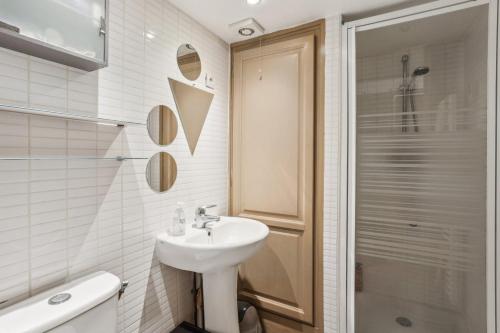 uma casa de banho branca com um lavatório e um chuveiro em Charmant appartement en plein coeur du Marais em Paris