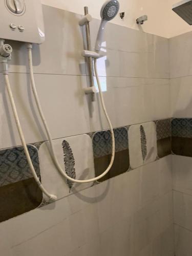 una ducha con una manguera pegada a la pared en R&R residencies en Mount Lavinia