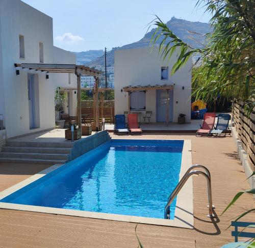 una piscina con sillas y una casa en Ios Endless Blue Luxury Bungalows, en Ios Chora