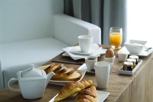 una mesa de desayuno con pastas y café y una tetera en Pol Hotel, en Le Touquet-Paris-Plage