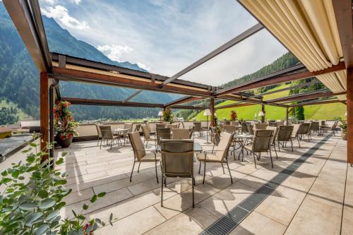 a patio with tables and chairs and mountains in the background at Wellness & Relax Hotel Milderer Hof in Neustift im Stubaital