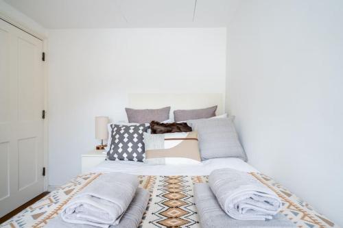 a bedroom with a bed with pillows on it at Spacious, Bright & Cosy ~ Ideal Victoria Location! in London