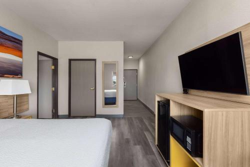 a hotel room with a bed and a flat screen tv at Days Inn & Suites by Wyndham Tucson/Marana in Tucson