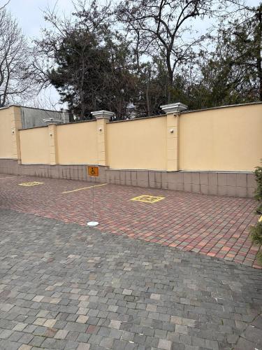 a brick parking lot with a fence and trees at Palace Del Mar in Odesa