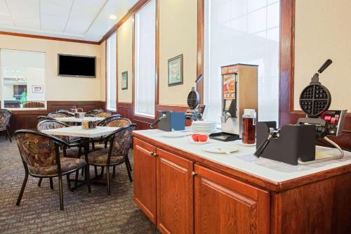a restaurant with a counter and a table and chairs at Ramada by Wyndham Red Deer Hotel & Suites in Red Deer