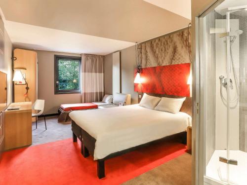 una camera d'albergo con letto e doccia di ibis Le Mans Est Pontlieue a Le Mans