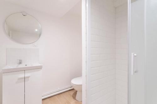 La salle de bains blanche est pourvue de toilettes et d'un miroir. dans l'établissement Lille Bel appartement Cosy avec Mezzanine, à Lille