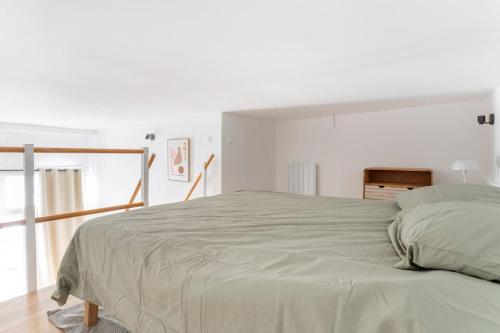 una camera bianca con un grande letto con una parete bianca di Lille Bel appartement Cosy avec Mezzanine a Lille