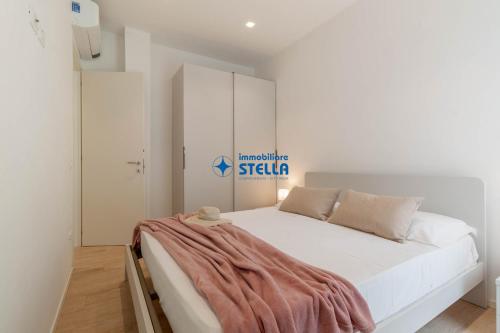 een slaapkamer met een wit bed met een deken erop bij Condominio Rossella in Lido di Jesolo