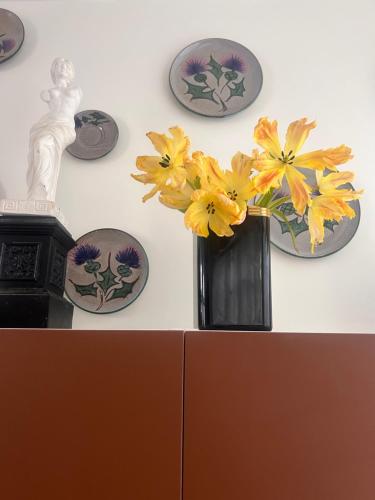 a vase with yellow flowers on a wall with plates at Maison Georges in Tourcoing