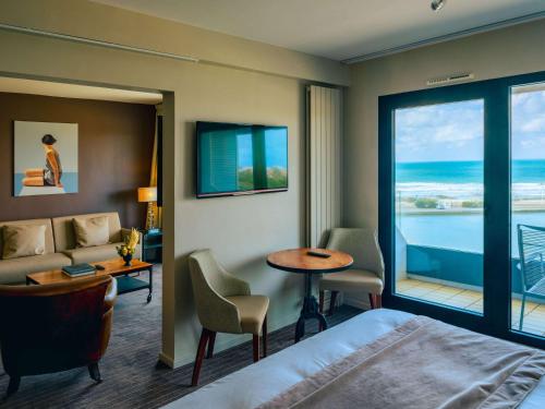 a hotel room with a bed and a view of the ocean at Côte Ouest Hôtel Thalasso & Spa Les Sables d'Olonne - MGallery in Les Sables-d'Olonne