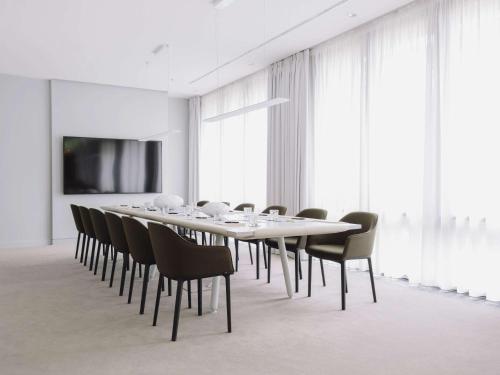 una sala conferenze con un lungo tavolo e sedie di Pullman Berlin Schweizerhof a Berlino